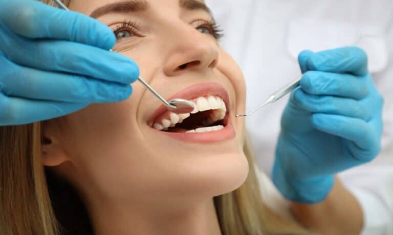 A woman receiving a dental checkup and cleaning, illustrating the steps and benefits of smile makeovers for achieving a beautiful and confident smile.
